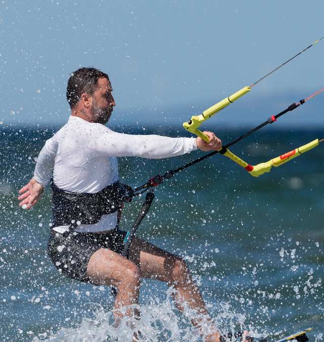 Su sıçratarak dönüş yapan kiteboardcu